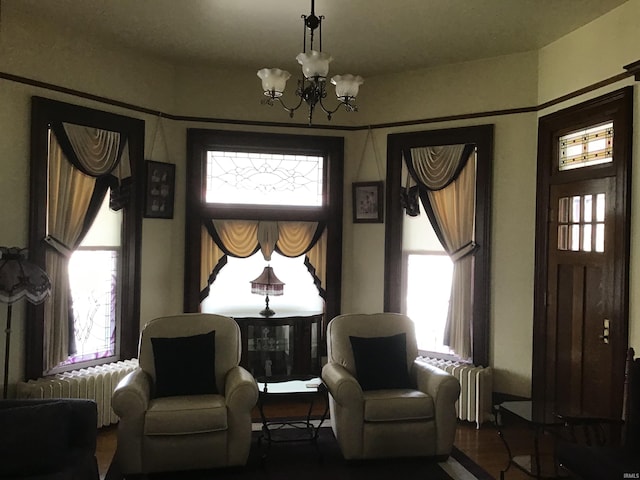 living area with radiator heating unit, plenty of natural light, and a notable chandelier