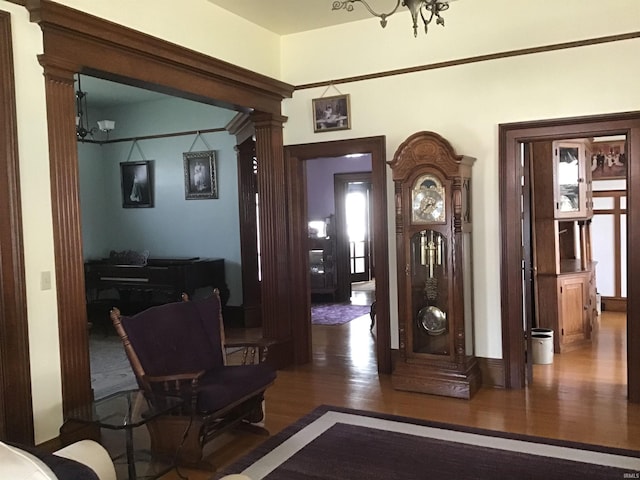 foyer entrance featuring ornate columns, baseboards, and wood finished floors