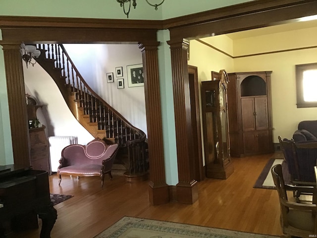 interior space with ornate columns, wood finished floors, radiator heating unit, and stairway