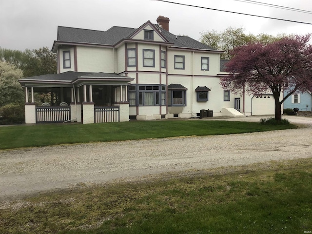 victorian home featuring dirt driveway, central air condition unit, a front lawn, a chimney, and a garage