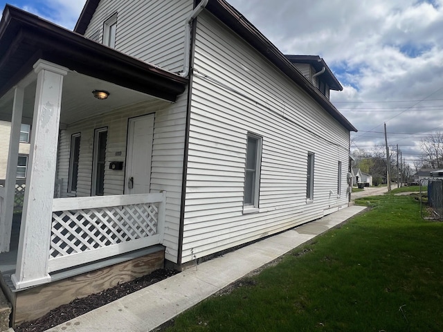 view of side of home with a porch and a yard