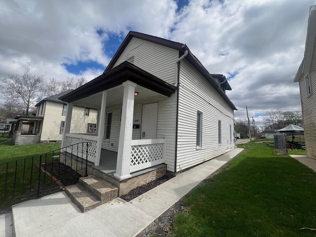 view of front facade featuring a porch, a front lawn, and fence