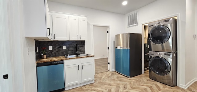 910 Harriet St, Evansville, IN 47710 - kitchen with tasteful backsplash, stacked washer and dryer, freestanding refrigerator, white cabinets, and dishwasher