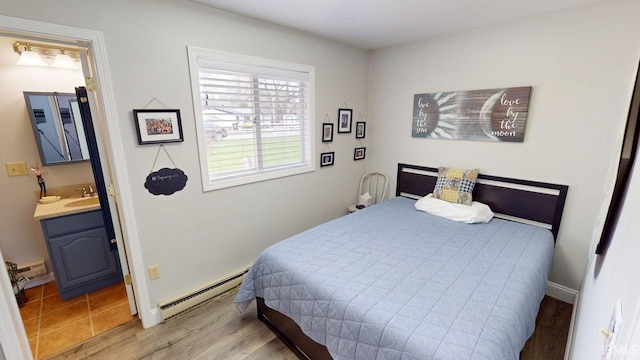 10509 N Lakeview Dr, Monticello, IN 47960 - bedroom with wood finished floors, ensuite bath, a baseboard radiator, a sink, and baseboards