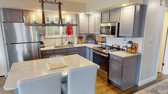 10509 N Lakeview Dr, Monticello, IN 47960 - kitchen featuring a sink, stainless steel appliances, tasteful backsplash, light wood-style flooring, and gray cabinetry