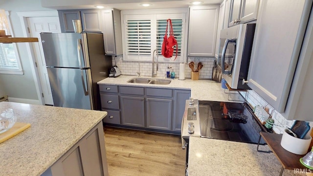 10509 N Lakeview Dr, Monticello, IN 47960 - kitchen featuring tasteful backsplash, a sink, appliances with stainless steel finishes, gray cabinetry, and light wood-type flooring