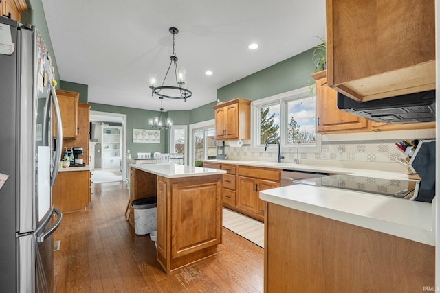 kitchen featuring a notable chandelier, light wood-style flooring, a center island, stainless steel appliances, and a sink