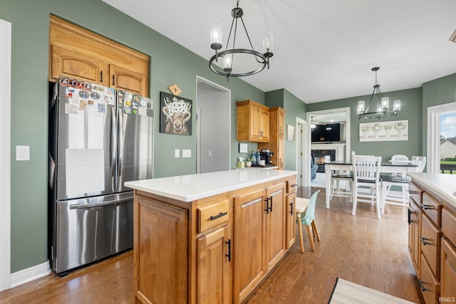 kitchen with an inviting chandelier, dark wood-style floors, light countertops, freestanding refrigerator, and pendant lighting