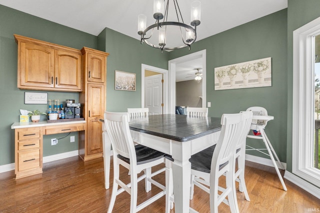 dining space featuring baseboards, an inviting chandelier, and wood finished floors
