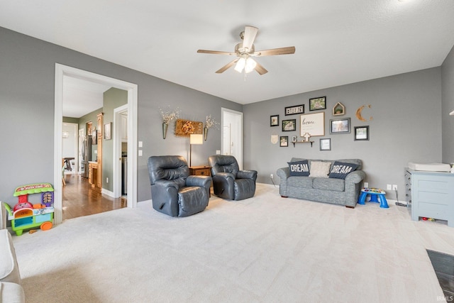living area featuring ceiling fan, baseboards, and carpet