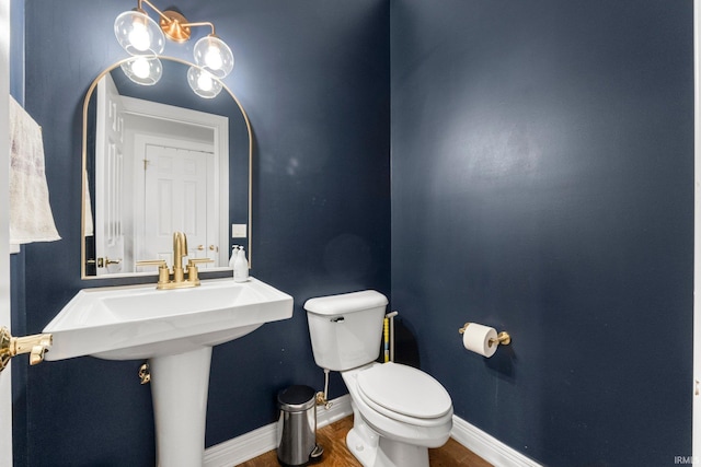 bathroom with toilet, wood finished floors, and baseboards