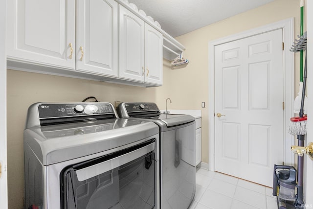 clothes washing area with cabinet space, light tile patterned floors, and separate washer and dryer
