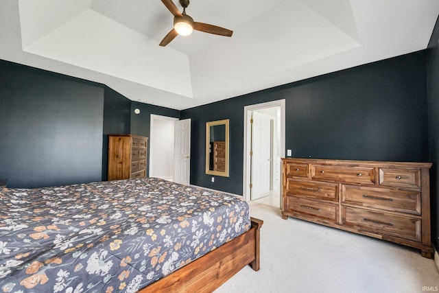 bedroom featuring light carpet, a ceiling fan, and a raised ceiling