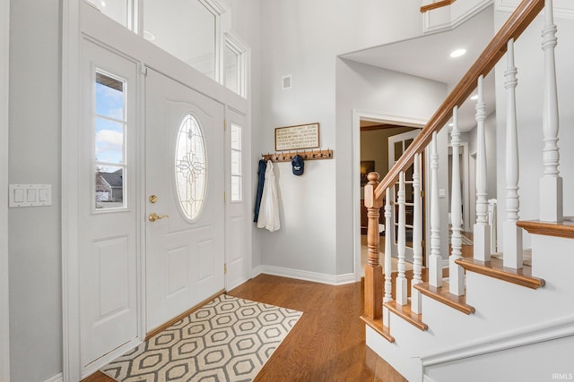 foyer entrance with baseboards, stairway, a towering ceiling, and wood finished floors