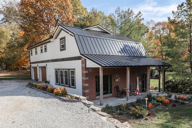 8780 N Old State Road 37th Rd, Bloomington, IN 47408 - rear view of house with an attached garage, metal roof, a patio, brick siding, and a standing seam roof
