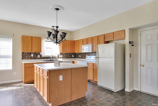 kitchen with tasteful backsplash, a notable chandelier, white appliances, and a kitchen island