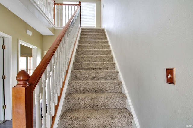 staircase featuring baseboards and a towering ceiling