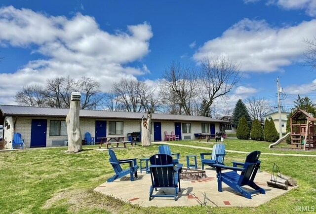342 E Himes St, North Webster, IN 46555 - rear view of house featuring a fire pit, a yard, metal roof, a playground, and a patio