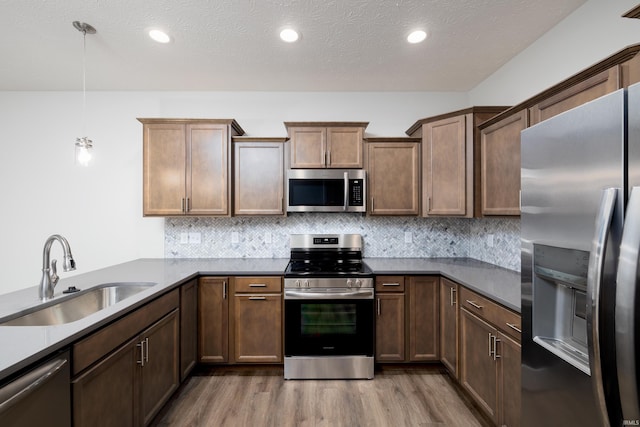 kitchen with decorative backsplash, appliances with stainless steel finishes, wood finished floors, and a sink