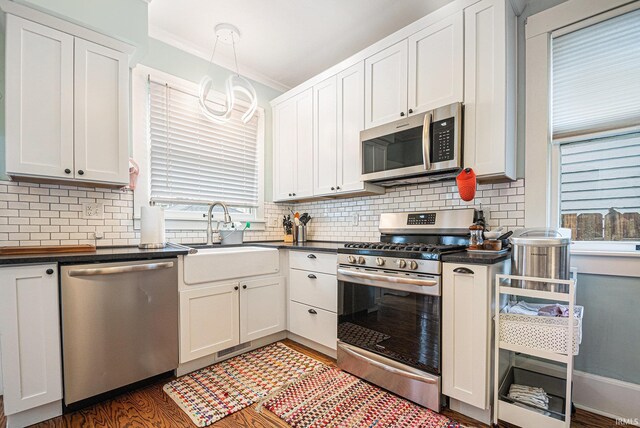 1069 Riverside Dr, South Bend, IN 46616 - kitchen with wood finished floors, dark countertops, a sink, stainless steel appliances, and a notable chandelier