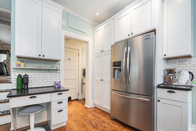 1069 Riverside Dr, South Bend, IN 46616 - kitchen with light wood-style floors, decorative backsplash, stainless steel fridge, and white cabinets