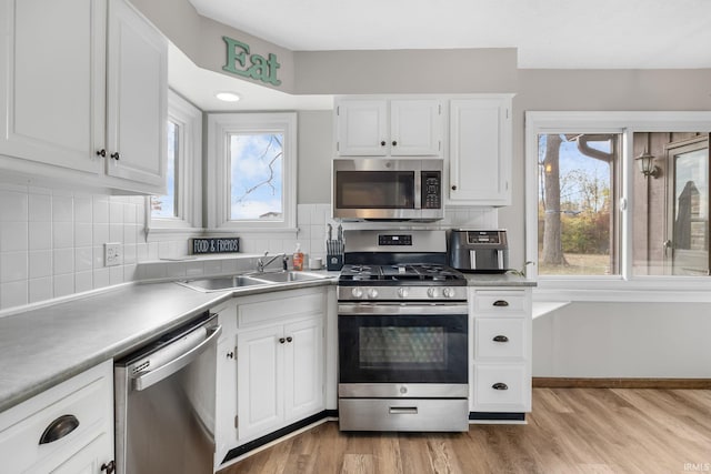 kitchen featuring light wood-type flooring, a sink, white cabinetry, and stainless steel appliances