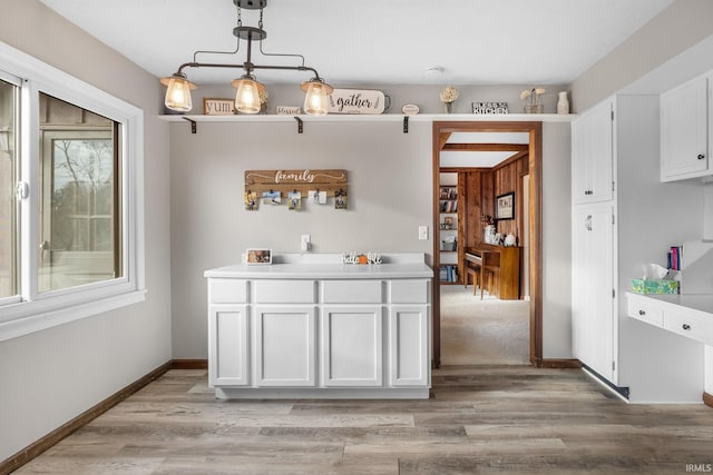 bar featuring baseboards, decorative light fixtures, and light wood-style floors