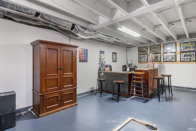 bar featuring finished concrete flooring, indoor bar, and concrete block wall