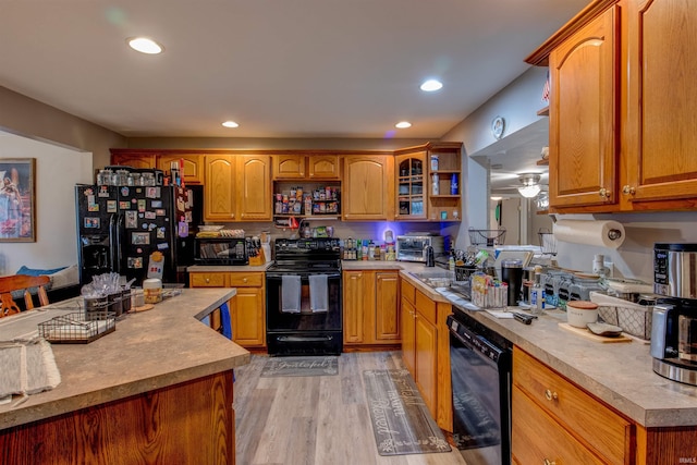 kitchen with light countertops, open shelves, light wood-style floors, brown cabinetry, and black appliances