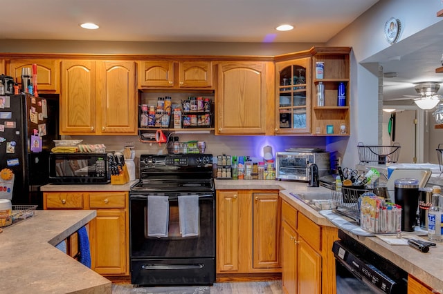 kitchen featuring glass insert cabinets, light countertops, black appliances, and a ceiling fan