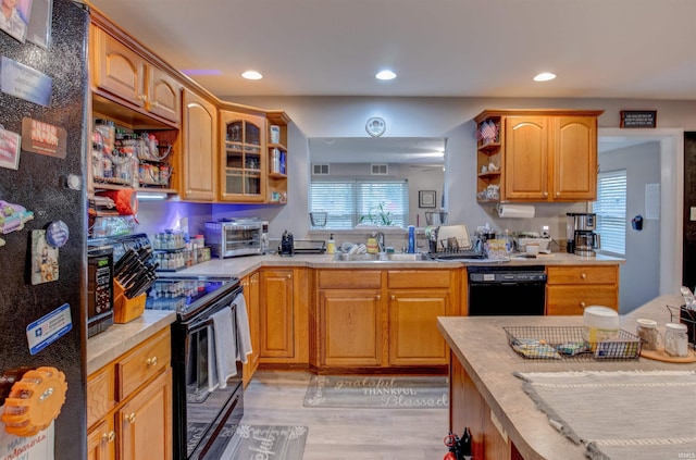 kitchen featuring light wood-style floors, open shelves, black appliances, light countertops, and a sink