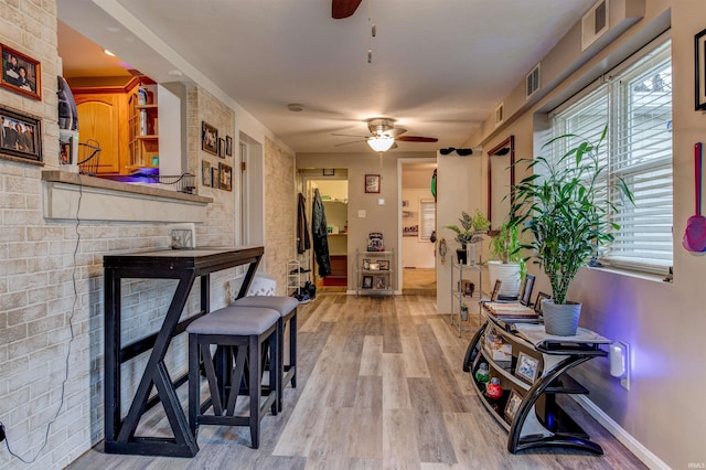 hall with visible vents, light wood-style flooring, and baseboards