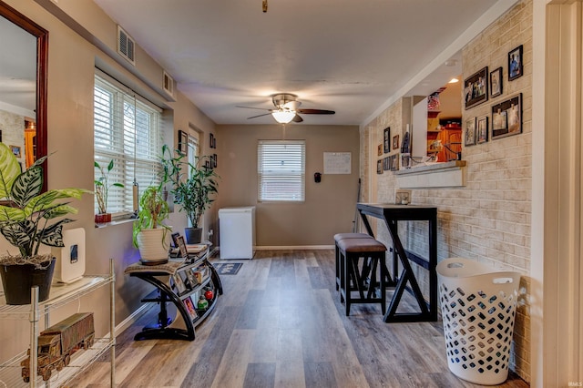 living area featuring baseboards, a fireplace, a ceiling fan, visible vents, and wood finished floors
