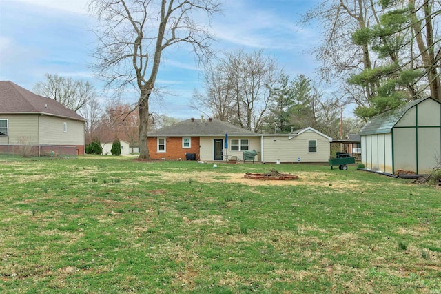 rear view of house with an outdoor fire pit, a yard, a storage unit, and an outdoor structure