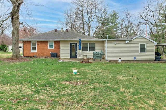 back of property featuring a yard, brick siding, and a carport
