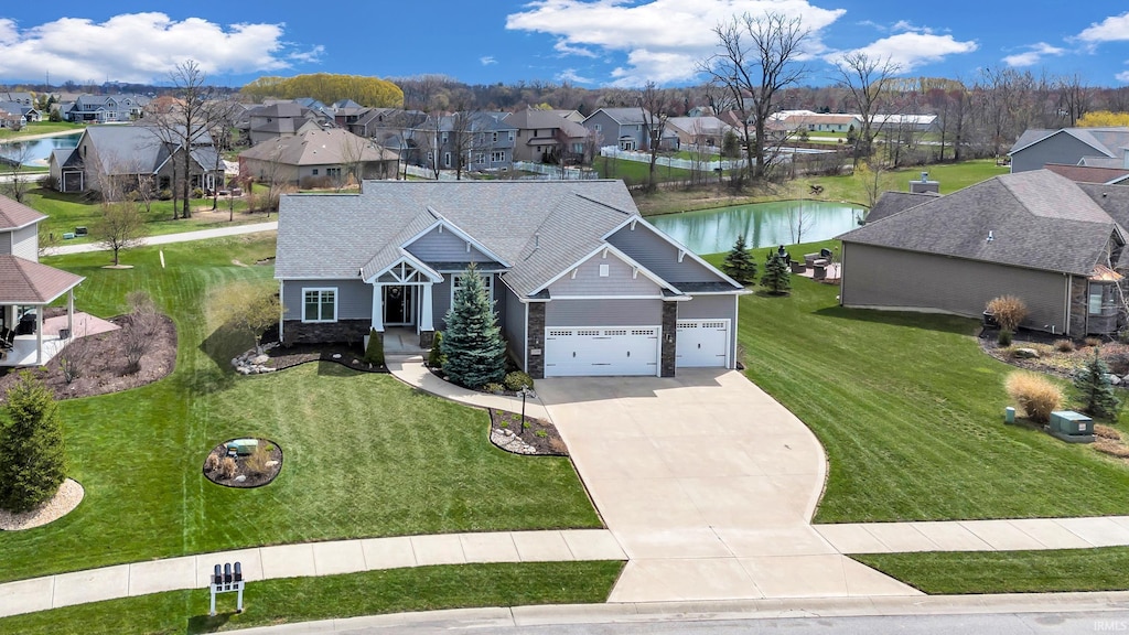 view of front of home with a water view, a front yard, stone siding, driveway, and a residential view