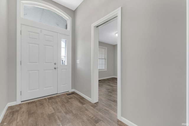 foyer with baseboards and light wood-style floors
