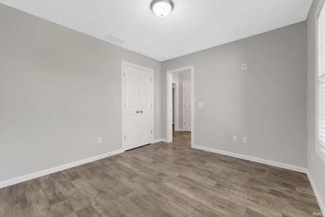 unfurnished bedroom with baseboards, wood finished floors, and a closet