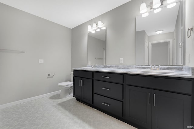 bathroom with baseboards, a sink, double vanity, and toilet