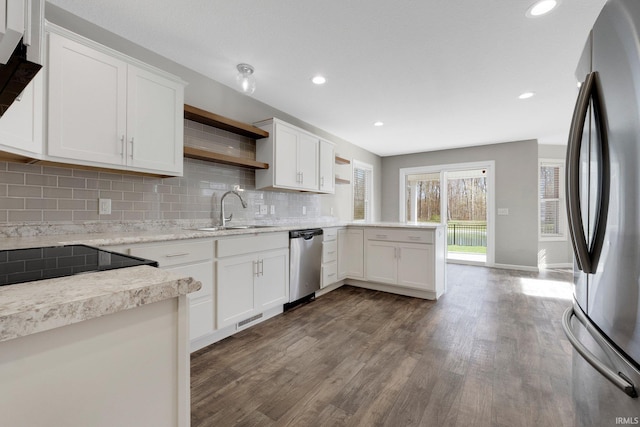 kitchen featuring open shelves, a sink, a peninsula, appliances with stainless steel finishes, and dark wood-type flooring