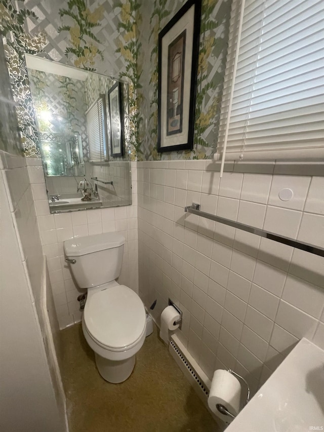bathroom featuring a wainscoted wall, toilet, tile walls, a baseboard radiator, and wallpapered walls