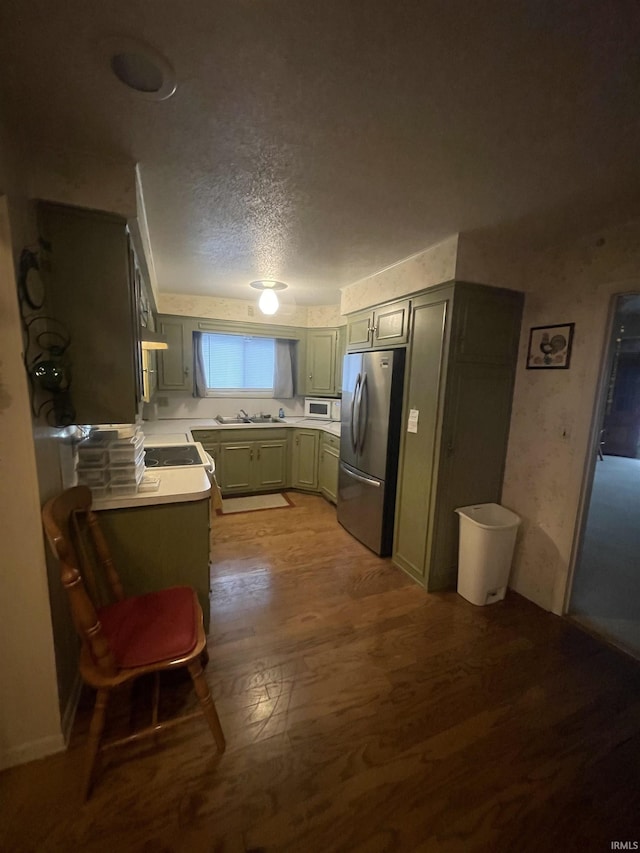 kitchen with freestanding refrigerator, a textured ceiling, wood finished floors, light countertops, and a sink