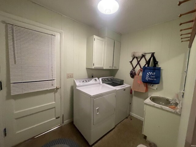 washroom featuring baseboards, washing machine and clothes dryer, a sink, and cabinet space