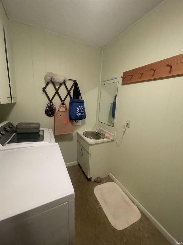 laundry area featuring dark colored carpet, baseboards, washing machine and dryer, cabinet space, and a sink