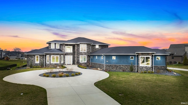 view of front facade featuring stucco siding, stone siding, a front lawn, and curved driveway