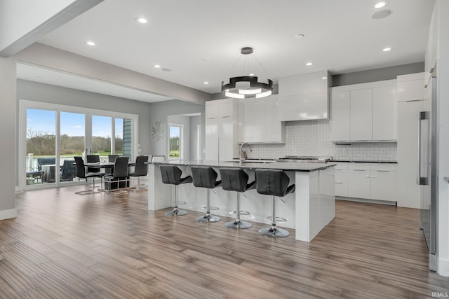 kitchen with a sink, wall chimney range hood, a kitchen bar, and modern cabinets