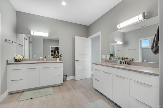 bathroom with two vanities, baseboards, and a sink