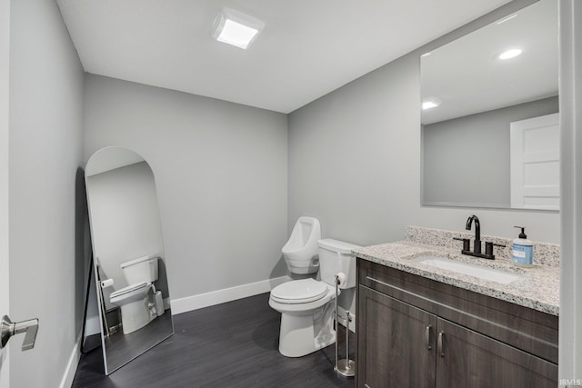 half bathroom with vanity, recessed lighting, toilet, wood finished floors, and baseboards
