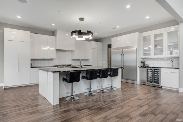 kitchen featuring tasteful backsplash, stainless steel built in refrigerator, dark countertops, modern cabinets, and a breakfast bar area