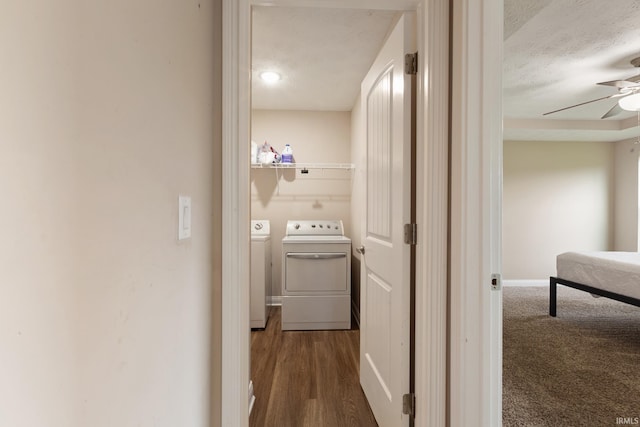 corridor featuring dark wood-type flooring, baseboards, separate washer and dryer, and a textured ceiling